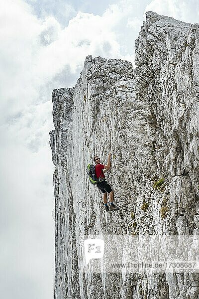 Junger Mann klettert an einer senkrechten Felswand ohne Seil  Felsige Berge und Geröll  beim Hochkalter  Berchtesgadener Alpen  Berchtesgadener Land  Oberbayern  Bayern  Deutschland  Europa