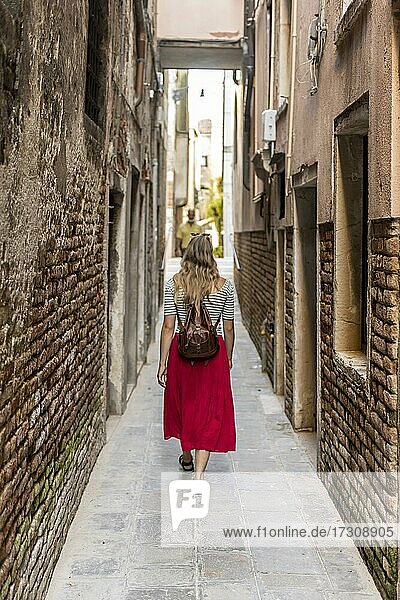 Junge Frau in Rotem Kleid geht durch enge Gasse  Venedig  Venetien  Italien  Europa