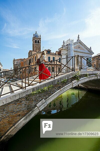 Junge Frau in Rotem Kleid geht über eine Brücke an einem Kanal  Venedig  Venetien  Italien  Europa