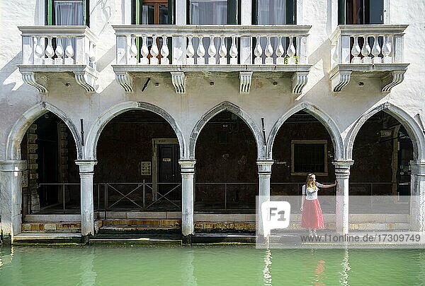 Junge Frau steht in einem Säulengang an einem Kanal  Venedig  Venetien  Italien  Europa