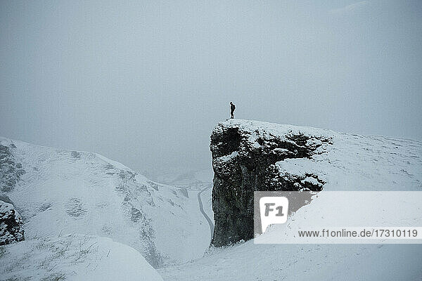 Wanderer auf abgelegener schneebedeckter Klippe  Peak District National Park  England