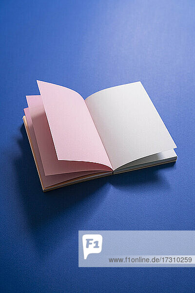 Leere Seiten im offenen Notizbuch auf blauem Hintergrund
