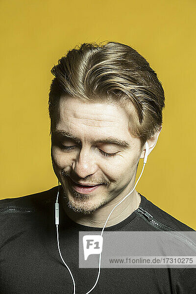 Porträt Mann hört Musik mit Kopfhörer auf gelbem Hintergrund