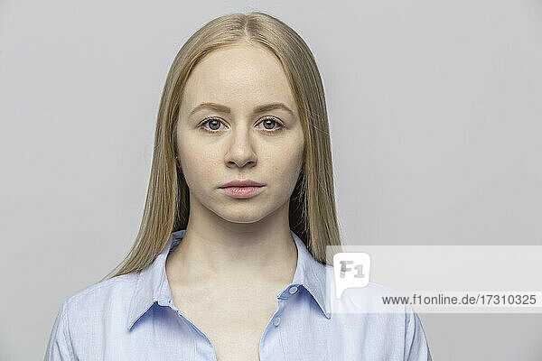 Porträt ernste junge Frau gegen grauen Hintergrund