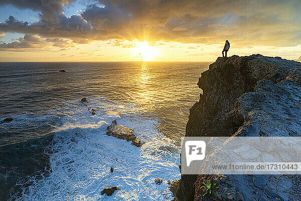 Ein Mann beobachtet Sonnenaufgang über den Ozean Wellen von Klippen  Madeira Insel  Portugal  Atlantik  Europa