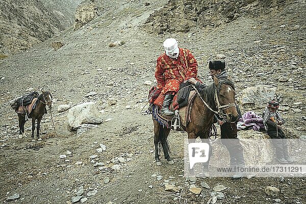 Ein Mann hilft seiner schwangeren Frau auf ein Pferd  kirgisische Nomaden  Wakhan-Korridor  Badachschan  Afghanistan  Asien