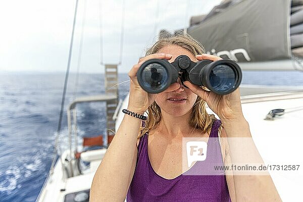 Young woman looking through binoculars  on sailboat  Dodecanese  Greece  Europe