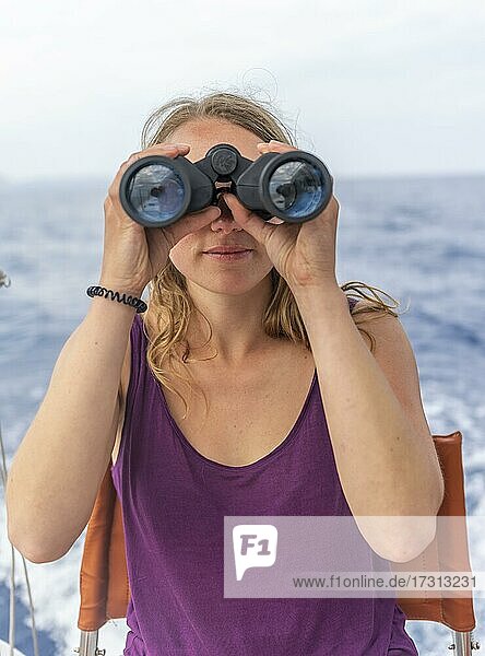 Young woman looking through binoculars  on sailboat  Dodecanese  Greece  Europe