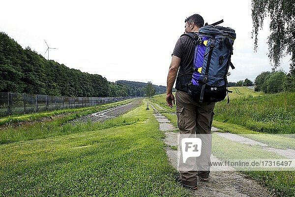Man with backpack  hiker  border fortification with column path  perforated plate path  K6  control strip  evidence strip  raked  uncovered field of vision and firing and border fence  expanded metal fence  border signal fence  barbed wire fence  inn
