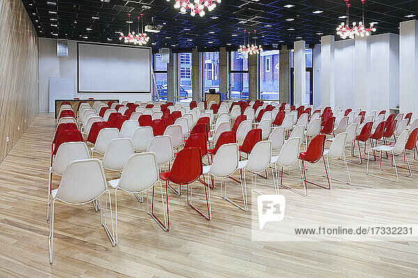 Großer leerer Raum mit roten und weißen Stühlen in Reihen