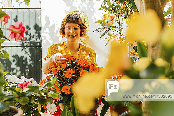 Lächelnde Frau bewundert Blumen im Hinterhof