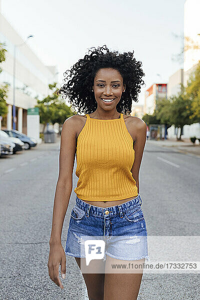 Smiling curly haired woman walking on street