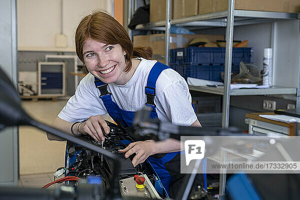 Smiling female technician looking away while working at workshop