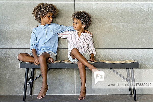 Boys with hand on shoulders looking at each other on bench