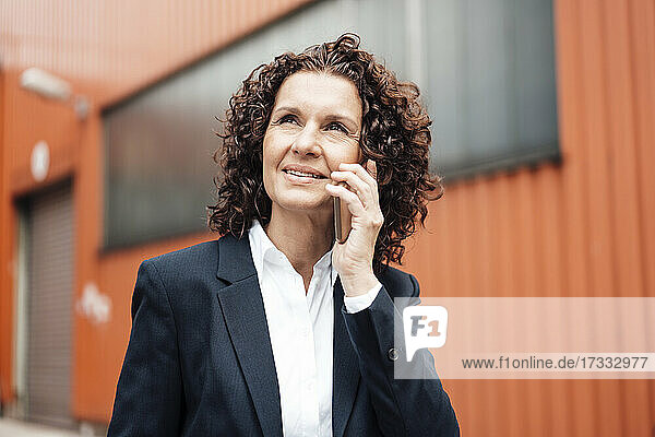 Geschäftsfrau schaut weg  während sie mit einem Mobiltelefon spricht