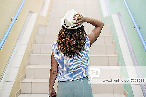Mittlere erwachsene Frau  die einen Hut trägt und auf einer Treppe steht