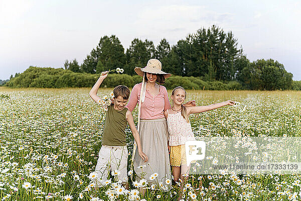 Mother standing with children amidst flowers in field