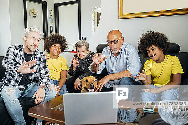 Begrüßung einer multiethnischen Familie während eines Videoanrufs auf dem Laptop zu Hause