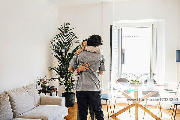 Paar umarmt sich gegenseitig  während es zu Hause steht