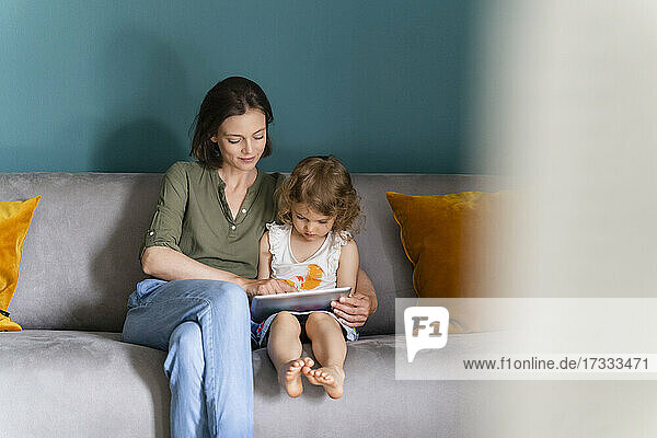 Mutter hilft ihrer Tochter beim Lernen zu Hause mit einem digitalen Tablet