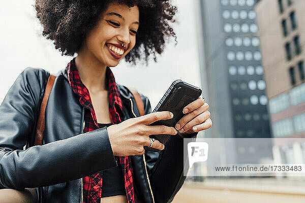 Lächelnde junge Frau mit Mobiltelefon