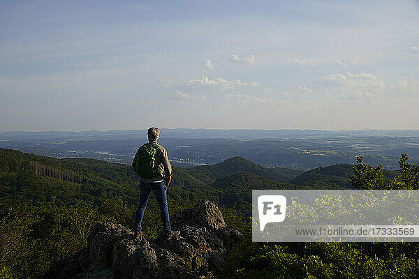 Männlicher Rucksacktourist betrachtet die malerische Landschaft  während er auf dem Gipfel eines Berges steht