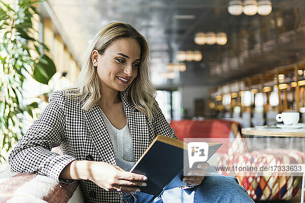 Smiling businesswoman reading book at cafe