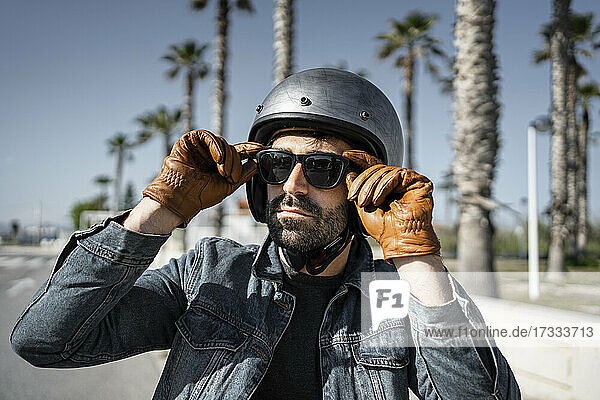 Handsome man in helmet wearing sunglasses on sunny day