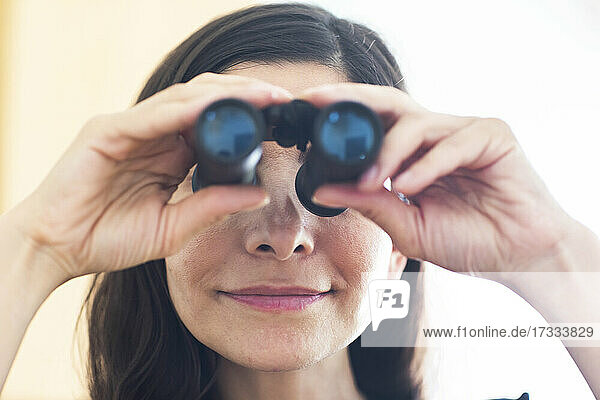 Female professional looking through binoculars in office