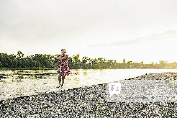 Playful woman dancing at riverbank