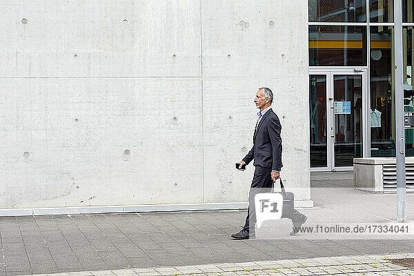 Männlicher Geschäftsmann mit Aktentasche in der Nähe eines Bürogebäudes