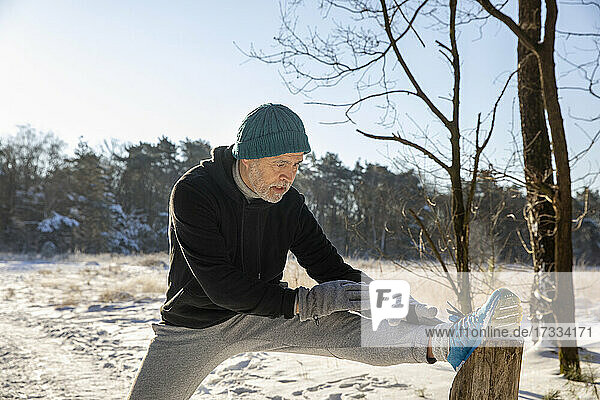 Älterer Mann streckt sein Bein beim Sport im Winter