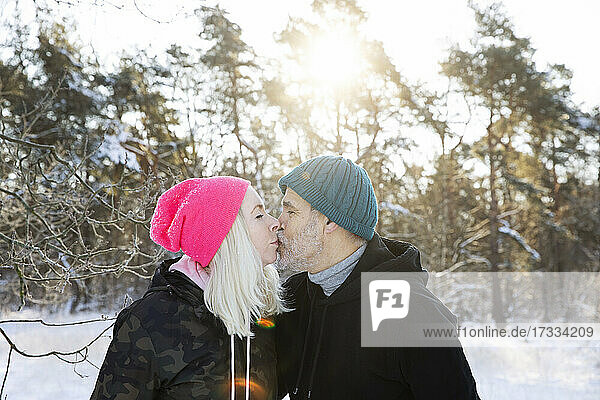 Paar mit Strickmützen  das sich im Winter küsst