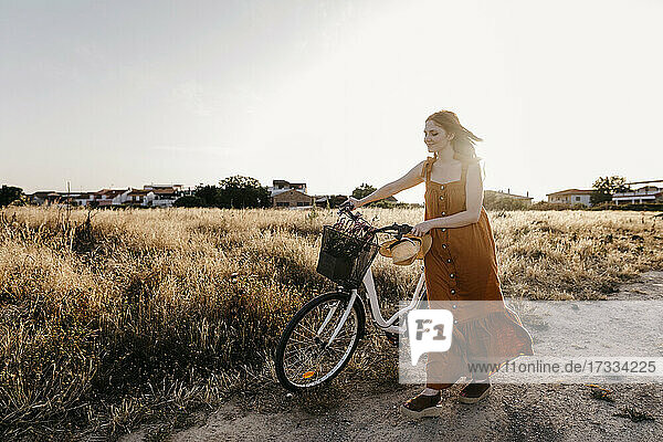 Junge Frau fährt Fahrrad auf einem Feld