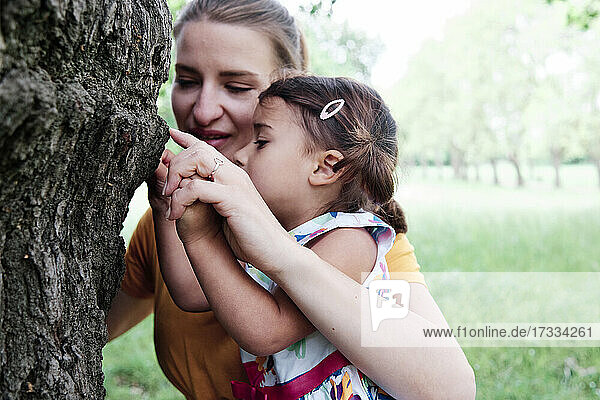 Mutter und Tochter berühren einen Baumstamm im Park