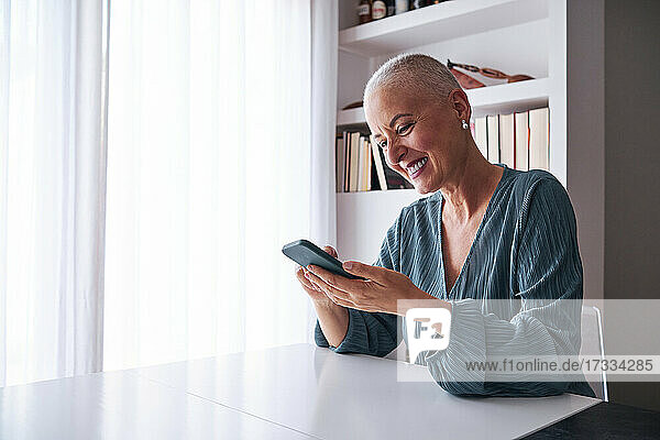 Mature woman using smart phone while sitting at home