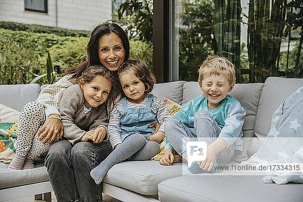 Lächelnde Mutter mit Kindern auf dem Sofa im Hinterhof
