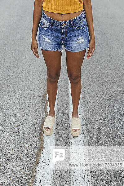 Young woman wearing denim shorts standing on road