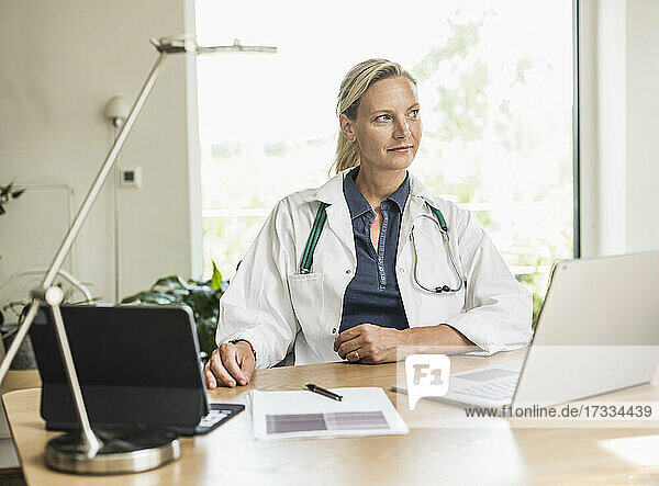 Thoughtful female doctor looking away while sitting at office