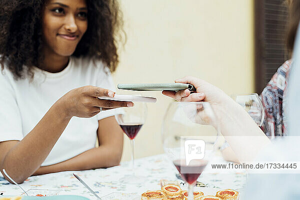 Freunde teilen sich ein Handy  während sie am Tisch sitzen