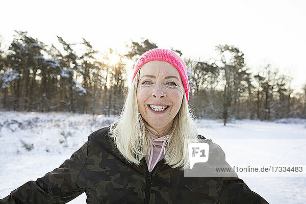 Happy blond woman wearing pink knit hat