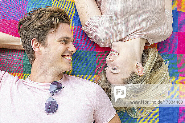Lächelndes Paar  das auf einer Picknickdecke von Angesicht zu Angesicht liegt