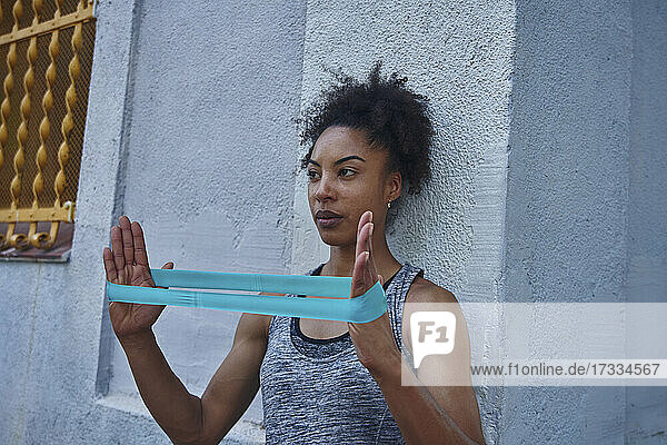 Mid adult woman exercising with resistance band in front of wall
