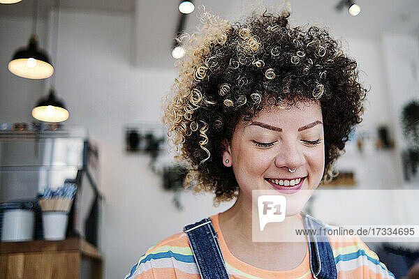 Junge Frau mit geschlossenen Augen lächelt in einem Cafe