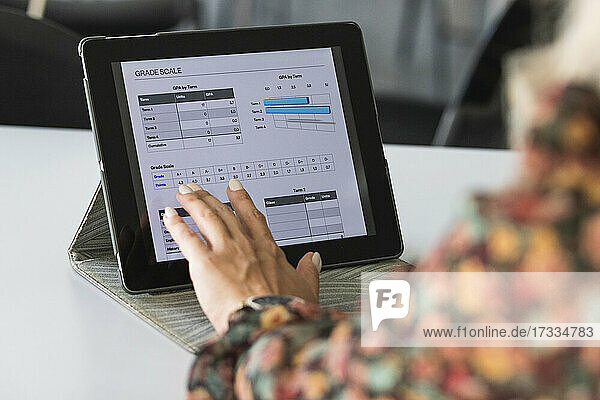 Female freelancer analyzing grade scale on digital tablet at coffee shop