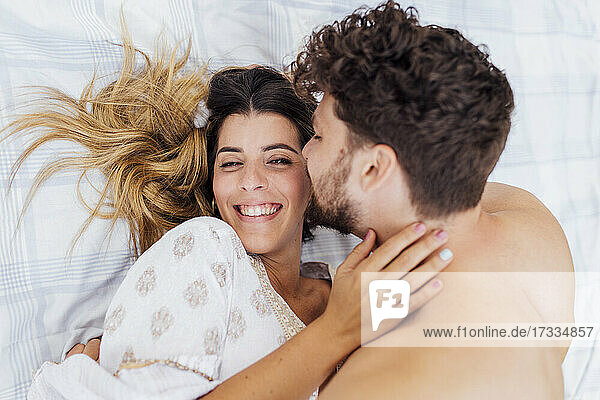Happy woman lying with shirtless boyfriend on picnic blanket