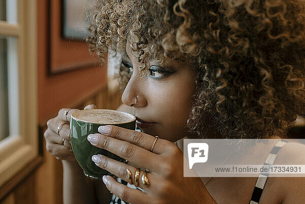 Thoughtful woman drinking coffee at cafe