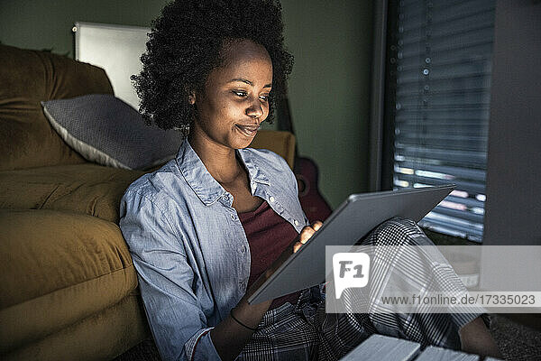 Smiling woman using digital tablet while sitting in living room