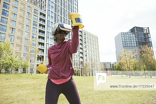 Aktive Frau beim Boxen mit Virtual-Reality-Headset im Park