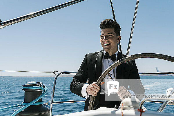 Lächelnder junger Mann beim Segeln auf einer Yacht im Sommer